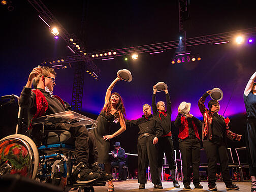 Eine Theatergruppe tanzt im Scheinwerferlicht