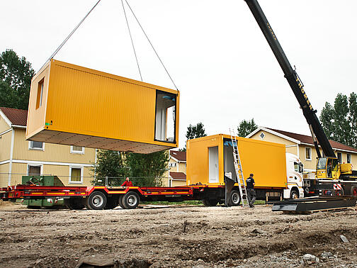 Gelbe Container werden mit einem Kran verladen 