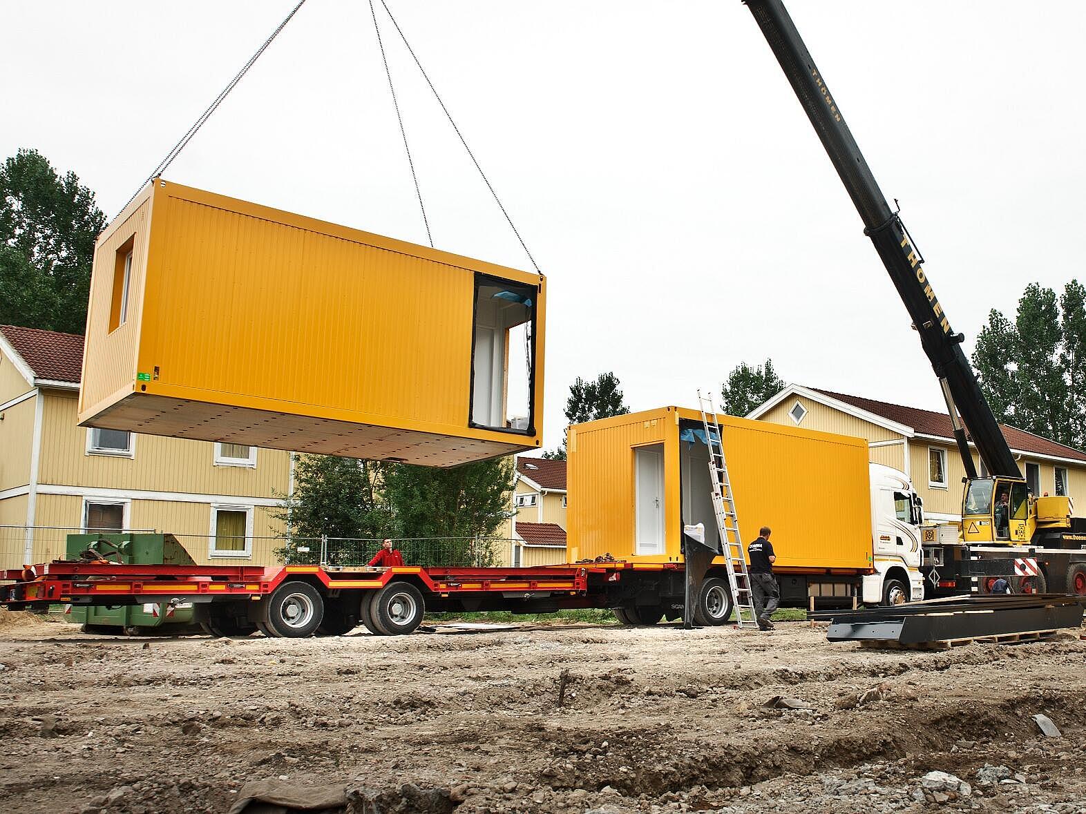 Gelbe Container werden mit einem Kran verladen 