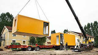 Gelbe Container werden mit einem Kran verladen