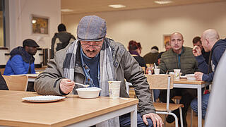 Ein Besucher des Winternotprogramms isst am Tisch.