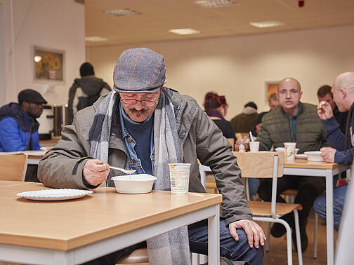 Ein Besucher des Winternotprogramms isst am Tisch. 