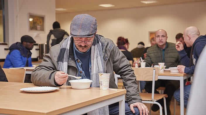 Ein Besucher des Winternotprogramms isst am Tisch. 