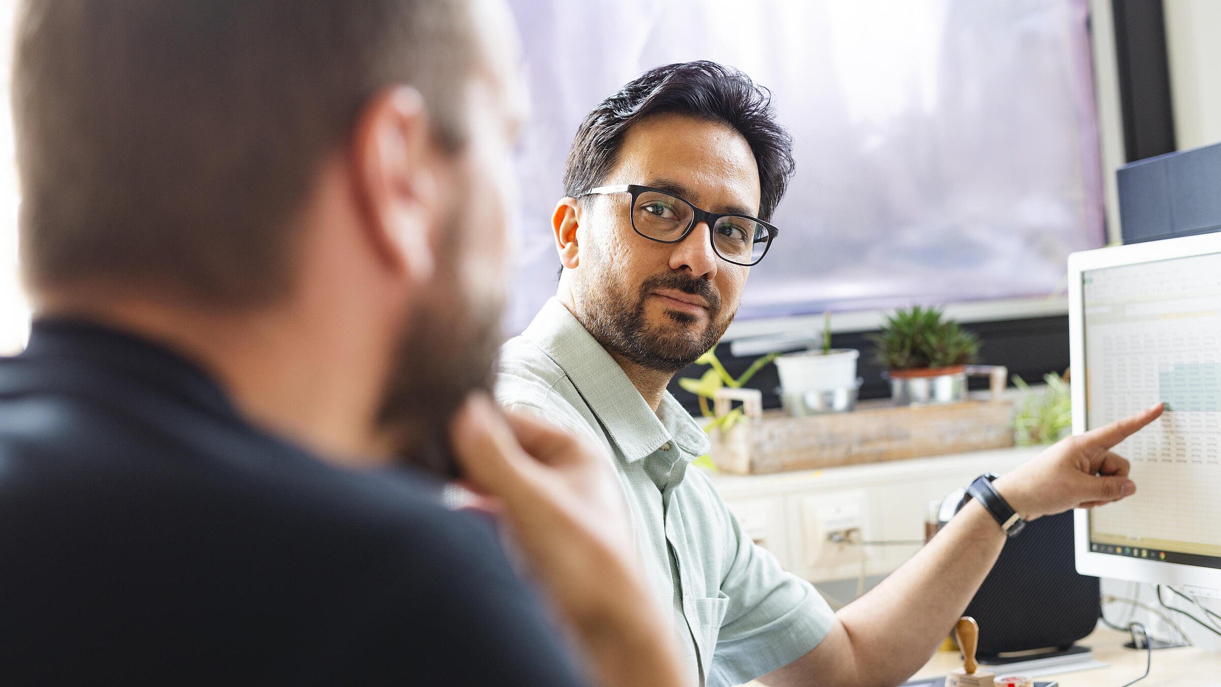 Gemeinsam mit seinem Arbeitskollegen bespricht Mohsen etwas am Computer