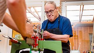 Ein Mann sägt an einer Werkbank