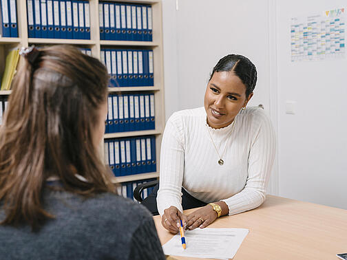 Mitarbeiterin berät eine Bewohnerin in einem Büro