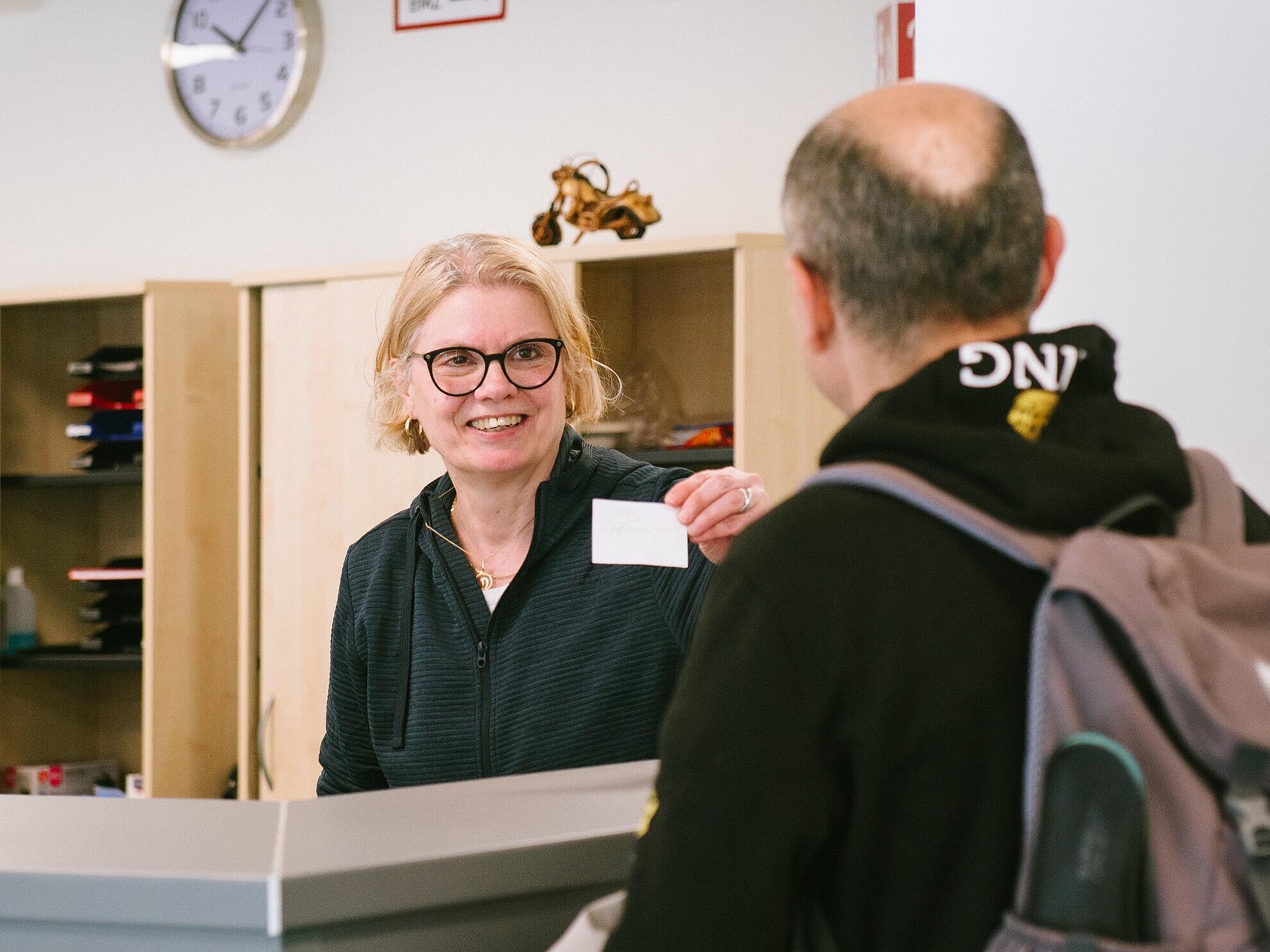 Eine Frau begrüßt einen Mann am Empfang
