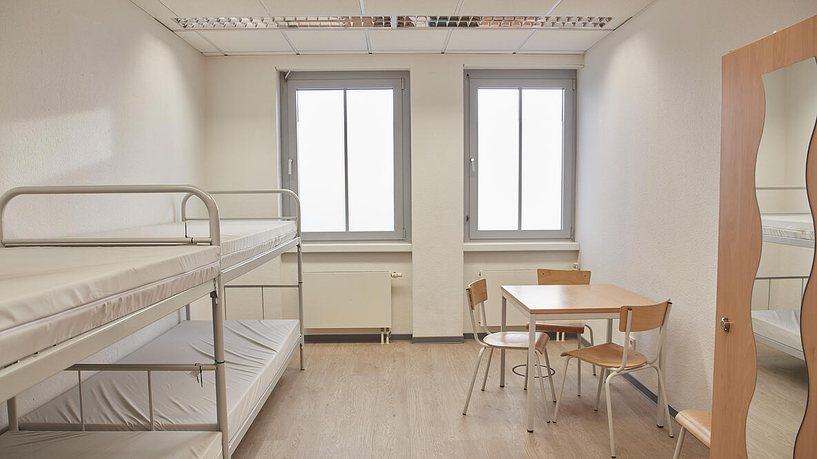 Zimmer mit Betten, Tisch und Schrank