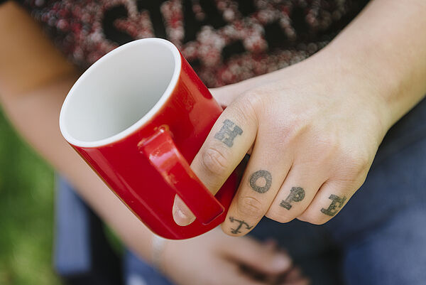Man sieht eine Hand mit einer Tasse 