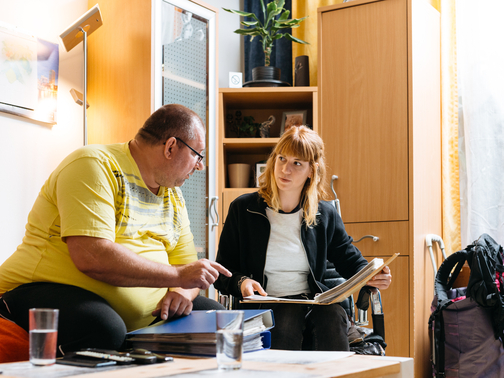 Mitarbeiterin aus der Sozialpädagogischen Einzelfallhilfe bespricht ein Dokument mit einem Klienten