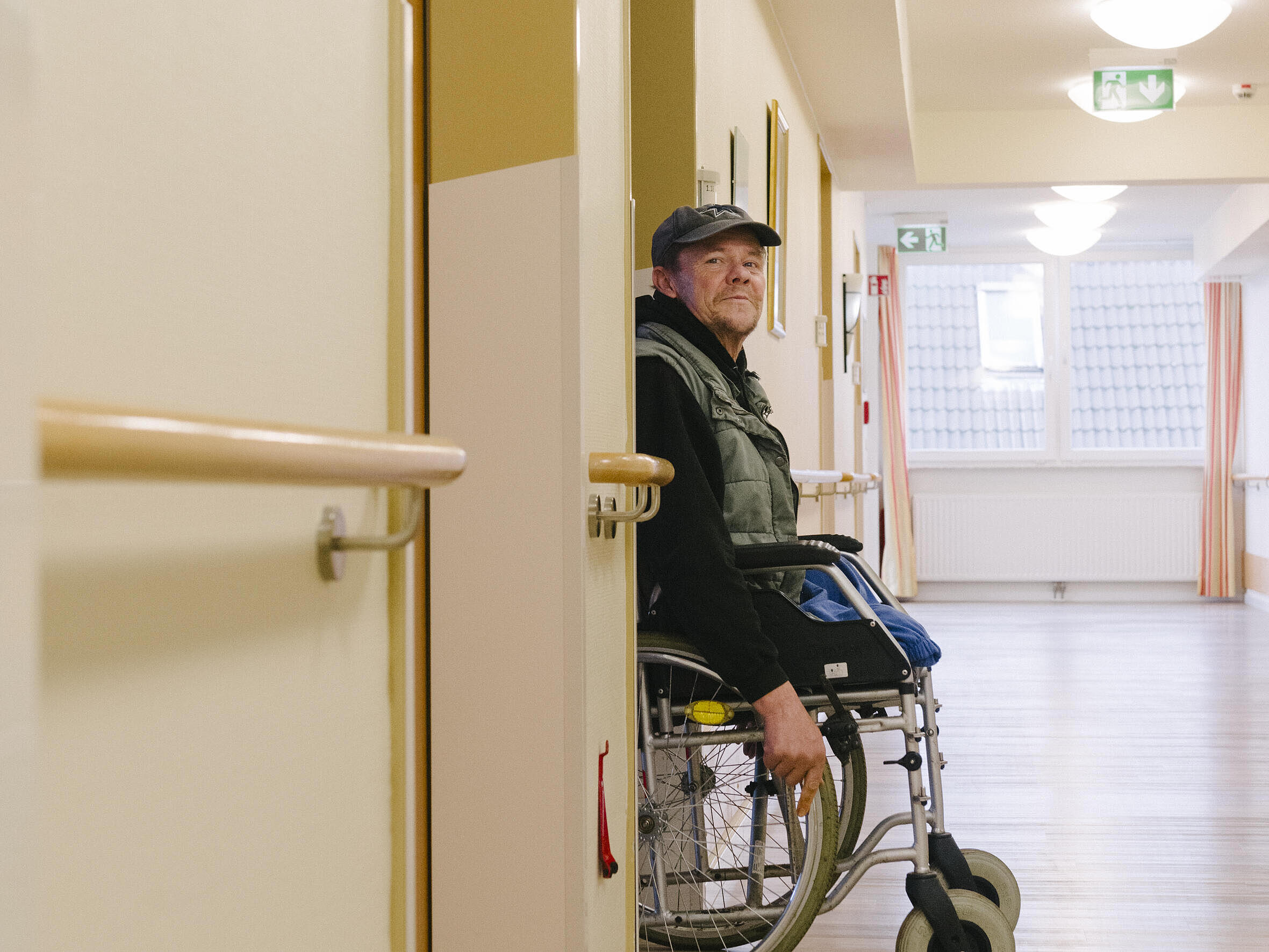Ein Mann mit Rollstuhl schaut aus einer Tür