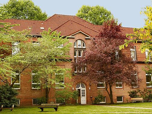 Ein altes Haus steht zwischen Bäumen. 