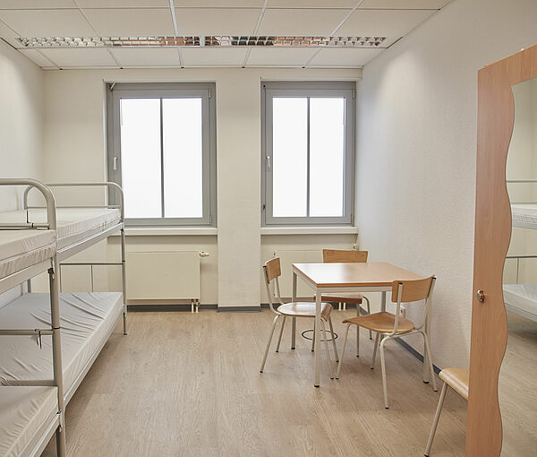 Zimmer mit Betten, Tisch und Schrank