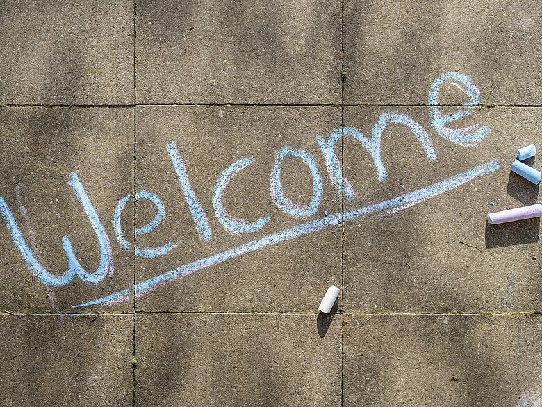 Symbolbild: Schriftzug Welcome in blauer Kreise auf Steinplatten