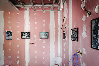 Bilder hängen an einer halb angemalten Wand