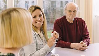 Eine junge Mitarbeiterin lächelt eine andere Frau an.