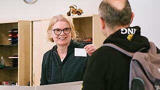 Eine Frau begrüßt einen Mann am Empfang