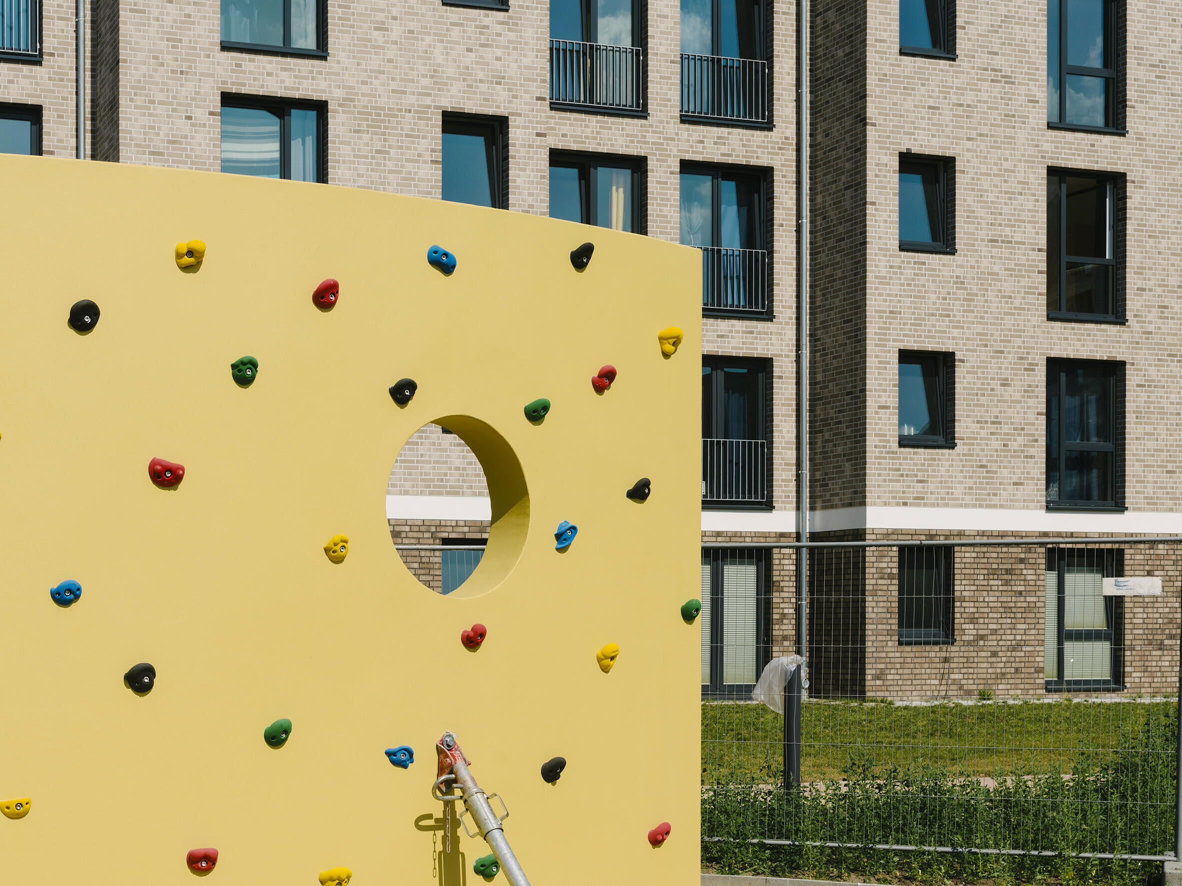 Eine Kletterwand vor einem Neubauhaus.