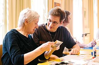 Ein Mitarbeiter und eine ältere Frau basteln
