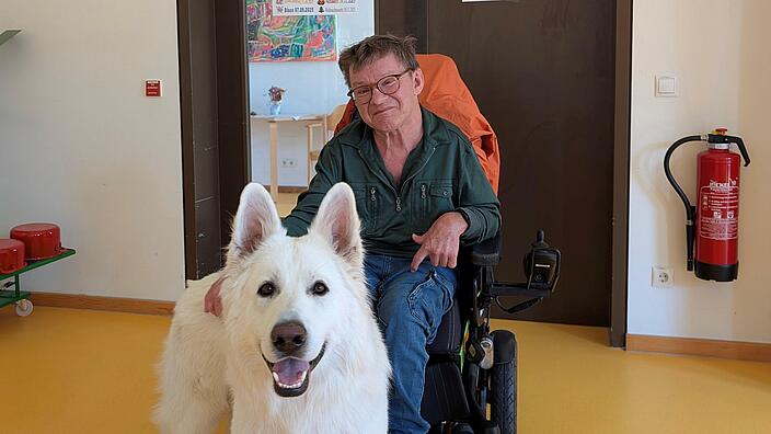 Ein Mann im Rollstuhl mit einem Hund 