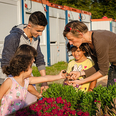 Freiwillige mit Kindern an einem Hochbeet