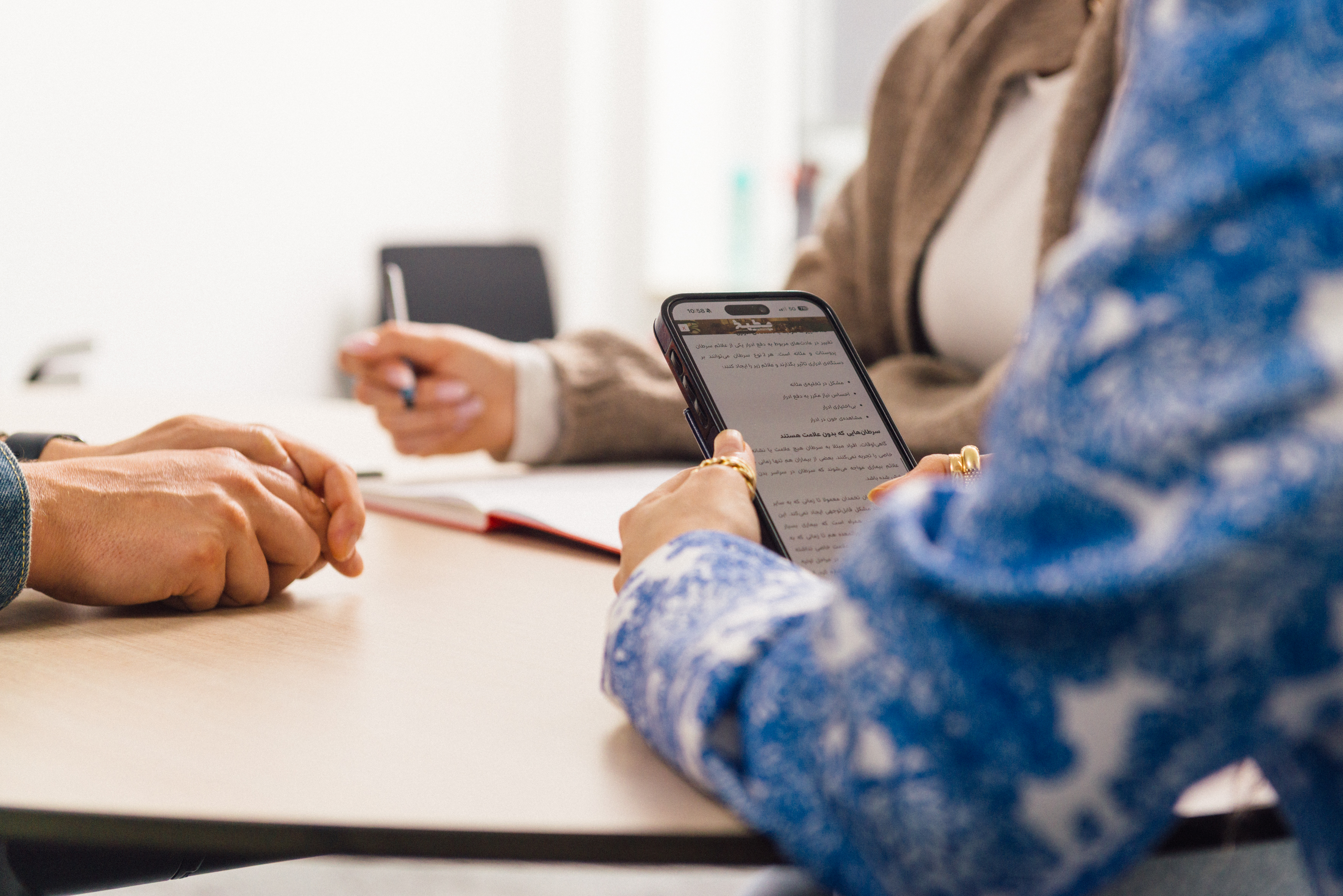 Hände halten ein Handy mit persischem Text 
