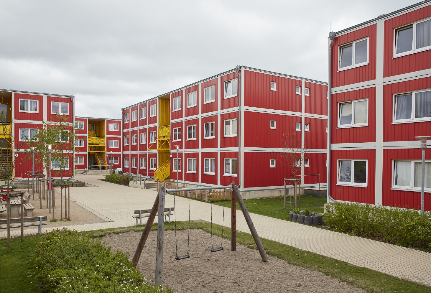 Die roten Containerhäuser der Unterkunft mit einem Spielplatz 